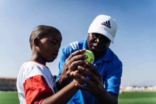 Cricket coach teaching a young player how to hold a cricket ball in South Africa